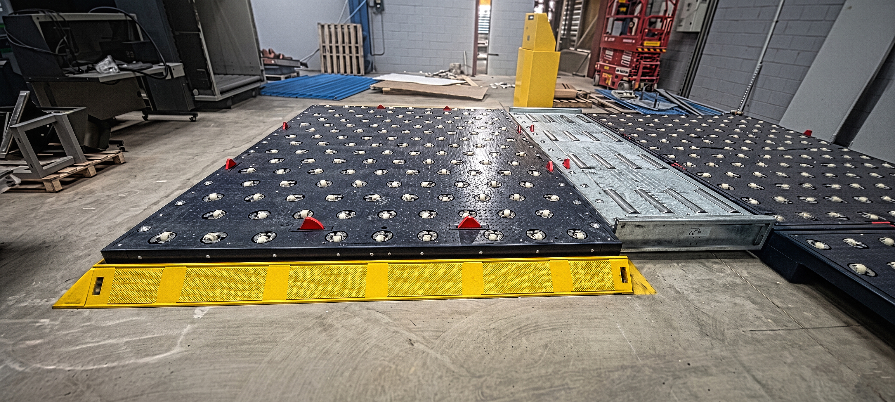 Báscula con plataforma rodante de bolas dobles para mover cargas pesadas con facilidad, vista lateral en taller industrial.
